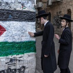 Miembros de Neturei Karta, una organización internacional de judíos ortodoxos antisionistas, posan junto a un mural que representa la bandera palestina durante una protesta contra el Estado de Israel, que consideran inexistente hasta la llegada del mesías, en el barrio de Mea Shearim, en Jerusalén, coincidiendo con la celebración del 78.º aniversario de la independencia de Israel. | Foto:ilia yefimovich / AFP