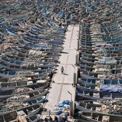 Un pescador camina junto a las piraguas atracadas en el Puerto Artesanal de Nouadhibou, Mauritania. | Foto:Patrick Meinhardt / AFP