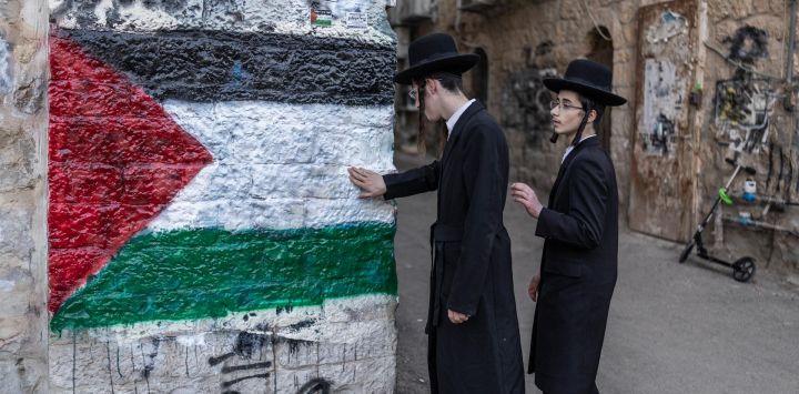 Miembros de Neturei Karta, una organización internacional de judíos ortodoxos antisionistas, posan junto a un mural que representa la bandera palestina durante una protesta contra el Estado de Israel, que consideran inexistente hasta la llegada del mesías, en el barrio de Mea Shearim, en Jerusalén, coincidiendo con la celebración del 78.º aniversario de la independencia de Israel.