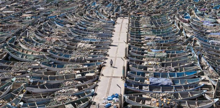 Un pescador camina junto a las piraguas atracadas en el Puerto Artesanal de Nouadhibou, Mauritania.