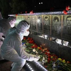 Participantes vestidos con trajes blancos de protección contra materiales peligrosos, en representación de los liquidadores, colocan velas frente a un monumento a las víctimas de Chernóbil durante una ceremonia de conmemoración del 40.º aniversario de la explosión en la central nuclear de Chernóbil, el peor desastre nuclear civil de la historia, en la ciudad de Slavutych, en medio de la invasión rusa de Ucrania. | Foto:GENYA SAVILOV / AFP