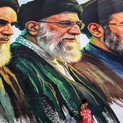 Un hombre se toma una selfie frente a una valla publicitaria que muestra a los difuntos líderes supremos de Irán, el ayatolá Ruhollah Khomeini (izquierda) y el ayatolá Ali Khamenei (centro), junto al recién elegido líder supremo Mojtaba Khamenei, en Srinagar. | Foto:TAUSEEF MUSTAFA / AFP