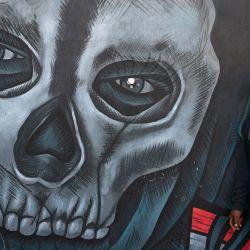 Un miembro del Comité de Desarrollo Campesino (CODECA) se encuentra junto a un mural durante una manifestación contra las medidas económicas, sociales y judiciales del gobierno del presidente Bernardo Arévalo en la Ciudad de Guatemala. | Foto:JOHAN ORDONEZ / AFP