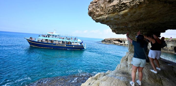 Imagen de turistas interactuados con visitantes a bordo de un yate cerca de una cueva marina, en Cabo Greco, en la costa sureste de Chipre.
