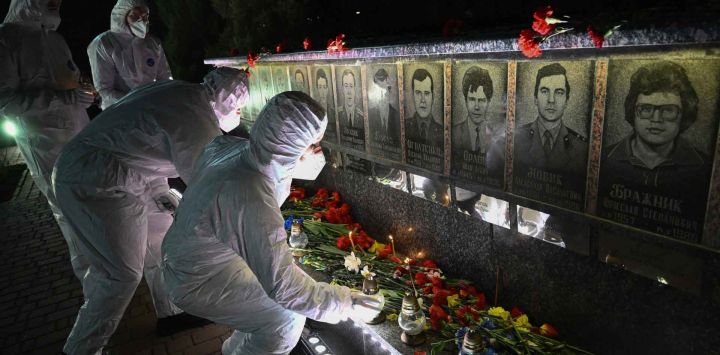 Participantes vestidos con trajes blancos de protección contra materiales peligrosos, en representación de los liquidadores, colocan velas frente a un monumento a las víctimas de Chernóbil durante una ceremonia de conmemoración del 40.º aniversario de la explosión en la central nuclear de Chernóbil, el peor desastre nuclear civil de la historia, en la ciudad de Slavutych, en medio de la invasión rusa de Ucrania.