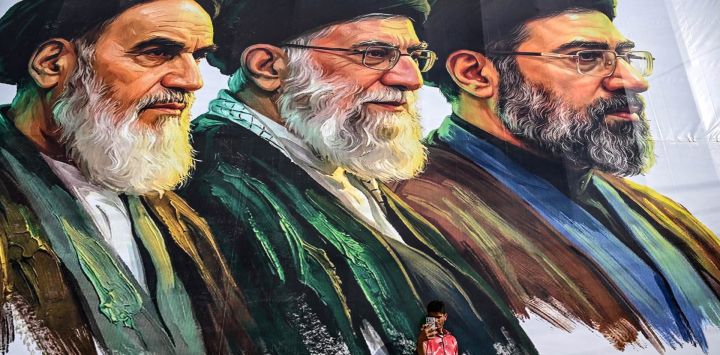 Un hombre se toma una selfie frente a una valla publicitaria que muestra a los difuntos líderes supremos de Irán, el ayatolá Ruhollah Khomeini (izquierda) y el ayatolá Ali Khamenei (centro), junto al recién elegido líder supremo Mojtaba Khamenei, en Srinagar.