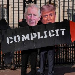 Dos miembros del grupo activista «Stop Trump Coalition» posan con un misil simulado y máscaras del rey Carlos III de Gran Bretaña y del presidente estadounidense Donald Trump frente a las puertas del Palacio de Buckingham, en el centro de Londres, para exigir el fin del apoyo del Reino Unido a Estados Unidos en los bombardeos sobre Irán. | Foto:CARLOS JASSO / AFP