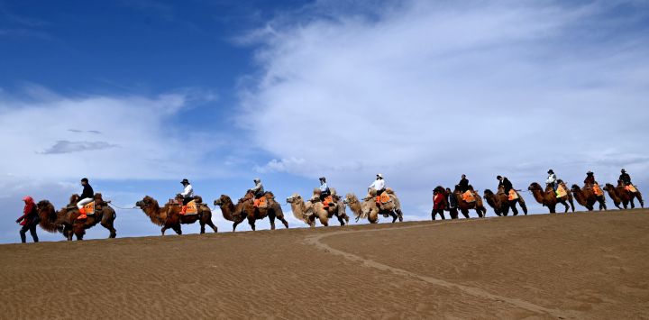 Turistas visitan el área escénica de la Montaña Mingsha y el Manantial de la Luna Creciente, en la ciudad de Dunhuang, en la provincia de Gansu, en el noroeste de China.