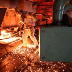 Un trabajador mueve una barra de acero al rojo vivo en un taller de fundición de acero en Lianyungang, en la provincia oriental china de Jiangsu. | Foto:CN-STR / AFP