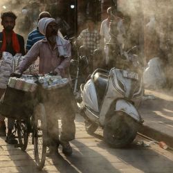 Varias personas caminan bajo los aspersores de agua instalados a lo largo de una calle en un caluroso día de verano en Varanasi, India. | Foto:NIHARIKA KULKARNI / AFP