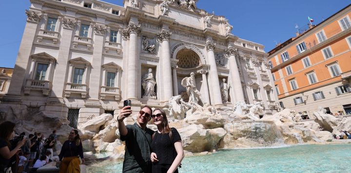 Imagen de turistas tomándose fotografías en la Fuente de Trevi, en Roma, Italia.