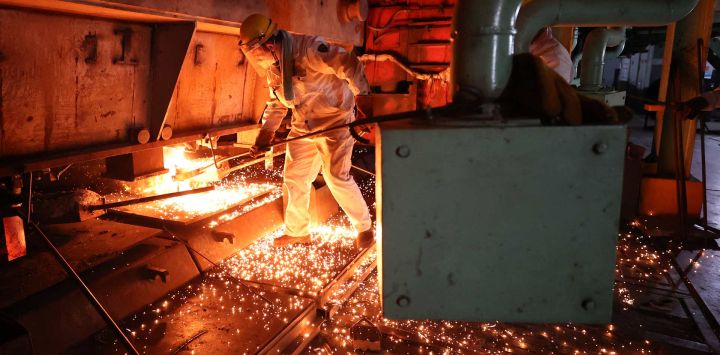 Un trabajador mueve una barra de acero al rojo vivo en un taller de fundición de acero en Lianyungang, en la provincia oriental china de Jiangsu.