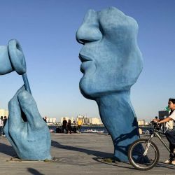 Una mujer pasa en bicicleta junto a una escultura en el lago Chitgar, un lago artificial recreativo y parque conocido oficialmente como el Lago de los Mártires del Golfo Pérsico, en el noroeste de Teherán. El ministro de Asuntos Exteriores de Irán regresó a Islamabad, Pakistán, para más consultas, mientras los mediadores internacionales intentaban mantener en marcha las conversaciones de paz a pesar de que el presidente de Estados Unidos canceló el viaje previsto de sus enviados. | Foto:ATTA KENARE / AFP