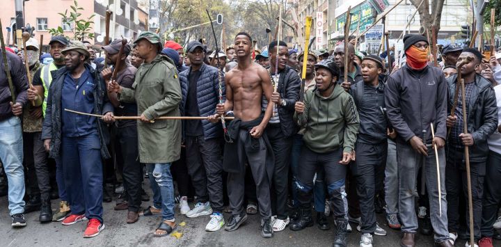 Manifestantes hacen gestos durante una marcha de protesta contra los inmigrantes indocumentados en Hillbrow, Johannesburgo, Sudáfrica.