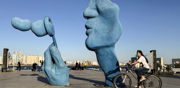 Una mujer pasa en bicicleta junto a una escultura en el lago Chitgar, un lago artificial recreativo y parque conocido oficialmente como el Lago de los Mártires del Golfo Pérsico, en el noroeste de Teherán. El ministro de Asuntos Exteriores de Irán regresó a Islamabad, Pakistán, para más consultas, mientras los mediadores internacionales intentaban mantener en marcha las conversaciones de paz a pesar de que el presidente de Estados Unidos canceló el viaje previsto de sus enviados.