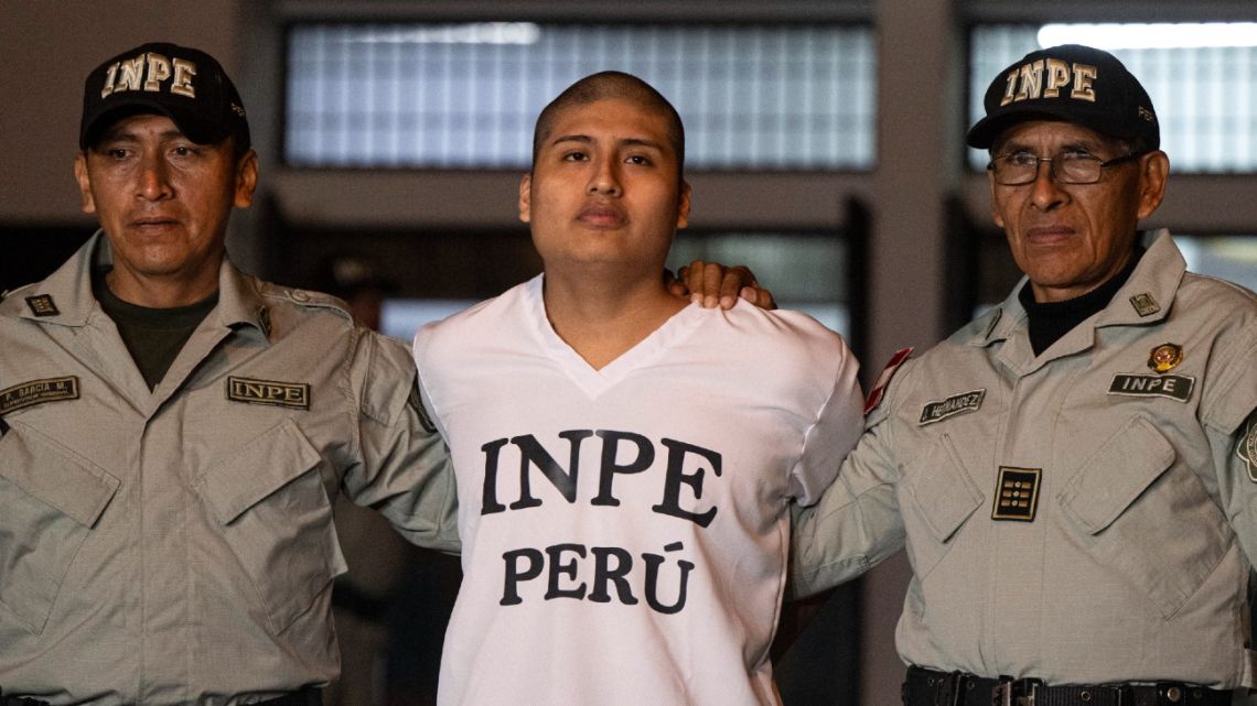 Agents of Peru’s National Penitentiary Institute (INPE) escort Tony Janzen Valverde Victoriano, alias ‘Pequeno J,’ the suspected mastermind behind the brutal murders of three young women in a live-streamed attack in Argentina, as he leaves the Ancon II…