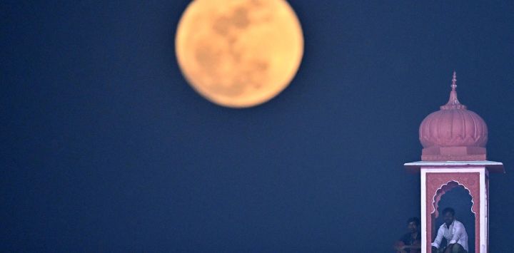 Los espectadores observan el partido de críquet T20 de la Indian Premier League (IPL) de 2026 entre los Rajasthan Royals y los Delhi Capitals mientras la luna llena se eleva sobre el estadio Sawai Mansingh en Jaipur, India.
