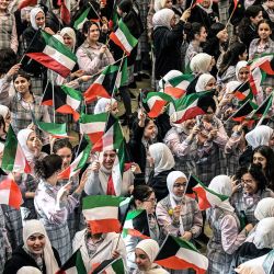 Estudiantes de secundaria ondean la bandera kuwaití mientras se reúnen en los terrenos de la escuela Fajr al-Sabah para asistir a clases presenciales en la ciudad de Kuwait. Los estudiantes de secundaria reanudaron las clases presenciales después de una suspensión de más de dos meses tras los ataques militares lanzados por Estados Unidos e Israel contra Irán que mataron a su líder supremo, desencadenando una guerra que se extendió por todo Oriente Medio y llevando al Ministerio de Educación kuwaití a implementar el aprendizaje a distancia para los estudiantes. | Foto:Yasser Al-Zayyat / AFP