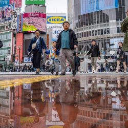 Varias personas cruzan el paso elevado de Shibuya mientras su reflejo brilla en un charco en Tokio, Japón. | Foto:Yuichi Yamazaki / AFP