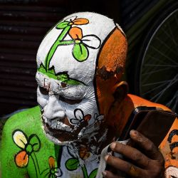 Un simpatizante con el símbolo electoral del partido All India Trinamool Congress (TMC) pintado en su cuerpo usa su teléfono móvil en una calle cercana a la residencia de la ministra principal de Bengala Occidental y presidenta del partido, Mamata Banerjee, en Calcuta, durante el recuento de votos para las elecciones a la Asamblea Legislativa de Bengala Occidental. El recuento de votos en las elecciones estatales clave de la India se llevó a cabo bajo estrictas medidas de seguridad, con la atención centrada en Bengala Occidental, donde el partido del primer ministro Narendra Modi parecía encaminarse a la victoria. | Foto:DIBYANGSHU SARKAR / AFP