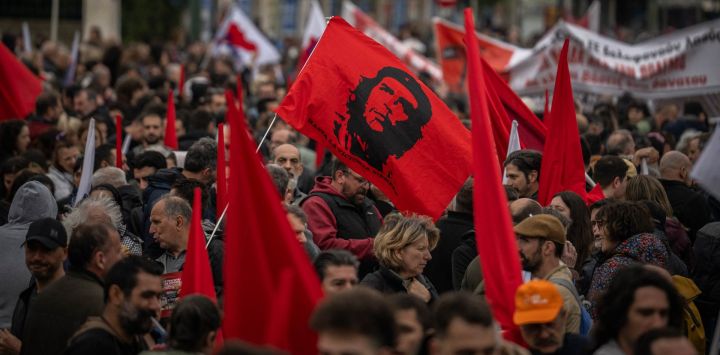 Manifestantes portan una bandera con la imagen del revolucionario cubano-argentino Ernesto "Che" Guevara durante una concentración en Atenas, Grecia.