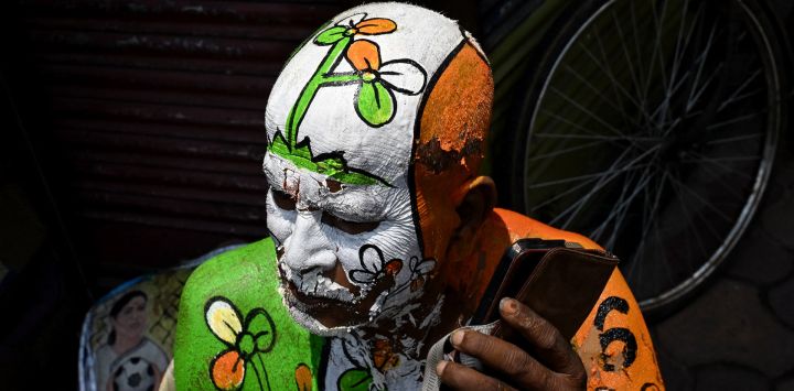 Un simpatizante con el símbolo electoral del partido All India Trinamool Congress (TMC) pintado en su cuerpo usa su teléfono móvil en una calle cercana a la residencia de la ministra principal de Bengala Occidental y presidenta del partido, Mamata Banerjee, en Calcuta, durante el recuento de votos para las elecciones a la Asamblea Legislativa de Bengala Occidental. El recuento de votos en las elecciones estatales clave de la India se llevó a cabo bajo estrictas medidas de seguridad, con la atención centrada en Bengala Occidental, donde el partido del primer ministro Narendra Modi parecía encaminarse a la victoria.