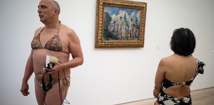 Visitantes en traje de baño pasan junto al cuadro "Baigneurs" ("Bañistas", 1890) del pintor francés Paul Cézanne durante la experiencia denominada "día de los bañistas" ("journée des baigneurs et des baigneuses"), inspirada por el artista italiano Maurizio Cattelan, con motivo de la exposición "Cézanne" en la Fundación Beyeler en Riehen, al norte de Suiza.