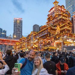 Imagen de turistas extranjeros tomándose fotografías frente al Area Escénica de Hongyadong, en el distrito de Yuzhong de Chongqing, en el suroeste de China. Mientras disfrutan de la deliciosa comida, contemplan los paisajes y experimentan la colorida cultura, los turistas extranjeros también se ven inmersos en la "sensación de seguridad china", que generalmente se refiere a la libertad de pasear solos a altas horas de la noche, la facilidad para recuperar pertenencias perdidas u olvidadas y la tranquilidad que se siente cuando los niños pequeños se divierten solos en la comunidad. | Foto:Xinhua/Huang Wei