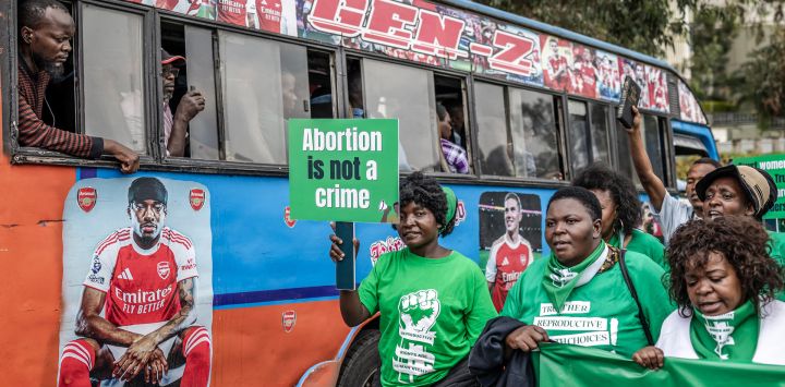 Activistas por los derechos reproductivos portan pancartas y corean consignas junto a un autobús público durante una marcha en defensa del acceso a la atención médica reproductiva y en protesta contra las leyes que penalizan el aborto y restringen los servicios de salud para mujeres y niñas en el centro de Nairobi, Kenia.