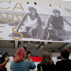 Trabajadores cuelgan el cartel oficial de la 79ª edición del Festival de Cine de Cannes en la fachada del Palais des Festivals mientras periodistas usan cámaras para capturar imágenes en Cannes, sureste de Francia. | Foto:Valery Hache / AFP