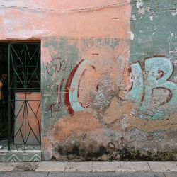 Una mujer se asoma por la puerta de su casa, junto a un muro con un grafiti que dice "CUBA", en una calle de La Habana, Cuba. La Habana acusó a Marco Rubio de "mentir" después de que el Secretario de Estado de Estados Unidos declarara que Washington no había impuesto un embargo petrolero a Cuba y atribuyera la actual crisis energética de la isla a una mala gestión interna. | Foto:YAMIL LAGE / AFP