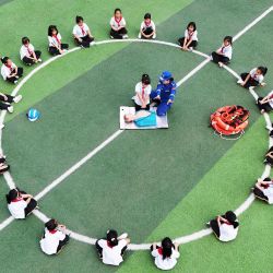Vista aérea tomada con un dron de un miembro del Equipo de Rescate Blue Sky demostrando una reanimación cardiopulmonar en una escuela primaria, en Tangshan, en la provincia de Hebei, en el norte de China. Una variedad de actividades se llevaron a cabo en todo el país con motivo del próximo Día Nacional de Prevención y Reducción de Desastres. | Foto:Xinhua/Zhu Dayong