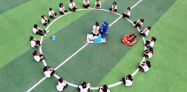 Vista aérea tomada con un dron de un miembro del Equipo de Rescate Blue Sky demostrando una reanimación cardiopulmonar en una escuela primaria, en Tangshan, en la provincia de Hebei, en el norte de China. Una variedad de actividades se llevaron a cabo en todo el país con motivo del próximo Día Nacional de Prevención y Reducción de Desastres.