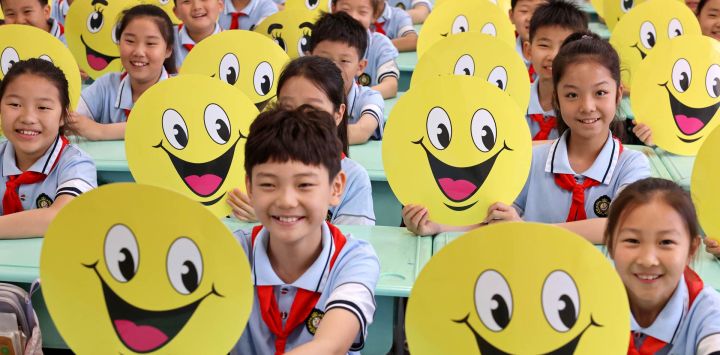 Estudiantes que sostienen tarjetas con caras sonrientes son vistos en una escuela primaria, en la ciudad de Zaozhuang, en la provincia de Shandong, en el este de China.