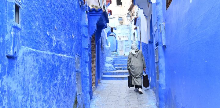 Imagen de una mujer caminando en un callejón, en Chefchaouen, Marruecos. Chefchaouen, conocida como la "ciudad azul" por sus paredes y callejones de colores, es un destino turístico en el norte de Marruecos.
