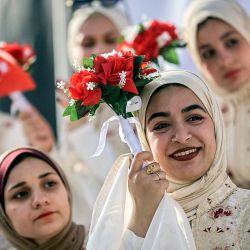 Novias a punto de contraer matrimonio observan durante una celebración de bodas colectivas para parejas palestinas organizada por la Fundación Turca de Ayuda Humanitaria (IHH) en la ciudad de Gaza. | Foto:OMAR AL-QATTAA / AFP