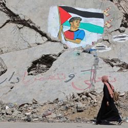 Una mujer pasa junto a un mural que representa al futbolista Lamine Yamal ondeando una bandera palestina durante el desfile de celebración del título del Catalán, pintado por artistas palestinos sobre los escombros de edificios destruidos durante la guerra, en el campamento de refugiados de Shati (Playa) en la ciudad de Gaza. El alto representante de Gaza en la Junta de Paz del presidente estadounidense Donald Trump declaró que el frágil alto el fuego en territorio palestino se mantenía a pesar de las violaciones diarias. | Foto:OMAR AL-QATTAA / AFP