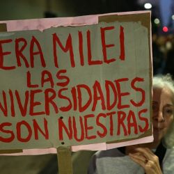 A woman holds a banner reading 'Get out Milei from the universities, they are ours' during a protest organized by university students and workers against the Javier Milei government's policies in Buenos Aires on May 12, 2026.