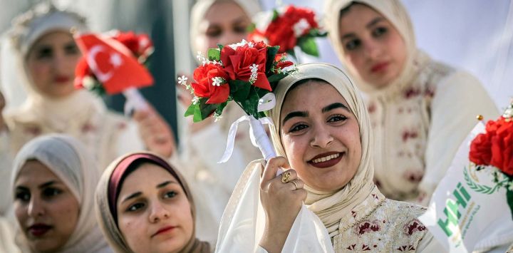 Novias a punto de contraer matrimonio observan durante una celebración de bodas colectivas para parejas palestinas organizada por la Fundación Turca de Ayuda Humanitaria (IHH) en la ciudad de Gaza.