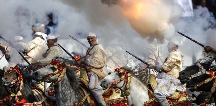 Hombres vestidos con atuendos tradicionales montan a caballo y disparan sus rifles durante una representación ecuestre de Tbourida, o Fantasía, en la ciudad de Bouznika, Marruecos.
