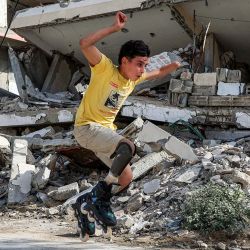 Akram al-Fayoumi, un palestino amputado de 13 años, realiza una acrobacia patinando con su prótesis de pierna junto a edificios destruidos en una calle de la ciudad de Gaza. Al-Fayoumi perdió la pierna derecha y la mano izquierda debido a un presunto bombardeo israelí contra la escuela Abdel Fattah Hammoud en el barrio de Tuffah, en la ciudad de Gaza. Posteriormente recibió tratamiento en Egipto y regresó a Gaza a finales de abril de 2026. | Foto:OMAR AL-QATTAA / AFP