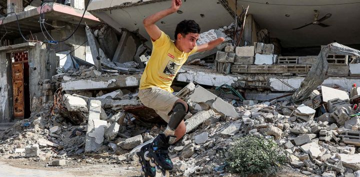 Akram al-Fayoumi, un palestino amputado de 13 años, realiza una acrobacia patinando con su prótesis de pierna junto a edificios destruidos en una calle de la ciudad de Gaza. Al-Fayoumi perdió la pierna derecha y la mano izquierda debido a un presunto bombardeo israelí contra la escuela Abdel Fattah Hammoud en el barrio de Tuffah, en la ciudad de Gaza. Posteriormente recibió tratamiento en Egipto y regresó a Gaza a finales de abril de 2026.