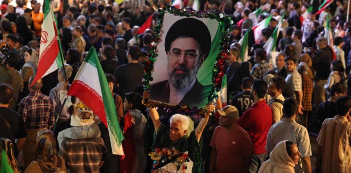 Un hombre sostiene un retrato del líder supremo de Irán, el ayatolá Mojtaba Khamenei, durante la ceremonia de despedida de la selección nacional de fútbol de Irán antes de su partida hacia la Copa Mundial de la FIFA 2026, en Teherán. El presidente de la Federación Iraní de Fútbol declaró que si Irán se retiraba del Mundial, el país perdería un "importante activo diplomático". La FIFA, organismo rector del fútbol mundial, ha insistido durante semanas en que Irán participará. Irán, que tendrá su sede en Tucson, Arizona, durante el Mundial, se enfrenta a Nueva Zelanda, Bélgica y Egipto en el Grupo G. Los iraníes debutarán en el Mundial contra Nueva Zelanda en Los Ángeles.