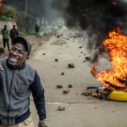 Un manifestante reacciona en una carretera bloqueada con una barricada en llamas y piedras para impedir el paso del tráfico durante una huelga nacional de transporte por el aumento del precio del combustible en Nairobi. El transporte público quedó prácticamente paralizado y los manifestantes bloquearon carreteras en Kenia, tras una huelga convocada por el aumento del precio del combustible provocado por la guerra en Oriente Medio. | Foto:LUIS TATO / AFP