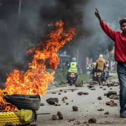 Un manifestante reacciona junto a una barricada en llamas en una carretera bloqueada con piedras para impedir el paso del tráfico durante una huelga nacional de transporte por el aumento del precio del combustible en Nairobi. El transporte público quedó prácticamente paralizado y los manifestantes bloquearon carreteras en Kenia tras una huelga convocada por el aumento del precio del combustible provocado por la guerra en Oriente Medio. | Foto:LUIS TATO / AFP