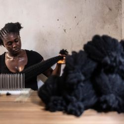 Una trabajadora coloca extensiones de cabello en un taller dentro del barrio chino de Ojota, en Lagos, Nigeria. | Foto:OLYMPIA DE MAISMONT / AFP
