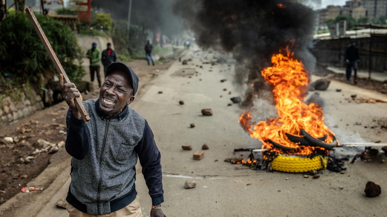 Un manifestante reacciona en una carretera bloqueada con una barricada en llamas y piedras para impedir el paso del tráfico durante una huelga nacional de transporte por el aumento del precio del combustible en Nairobi. El transporte público quedó prácticamente paralizado y los manifestantes bloquearon carreteras en Kenia, tras una huelga convocada por el aumento del precio del combustible provocado por la guerra en Oriente Medio. | Foto:LUIS TATO / AFP