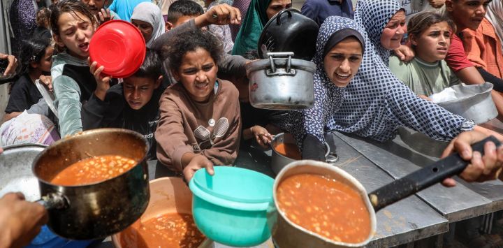 Palestinos reciben comida gratuita de una cocina comunitaria, en la Ciudad de Gaza.