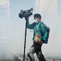 Un camarógrafo corre entre una nube de gas lacrimógeno durante los enfrentamientos entre mineros y la policía antidisturbios en una marcha para exigir la renuncia del presidente boliviano Rodrigo Paz, en La Paz. Los bolivianos han salido a las calles durante las últimas dos semanas, bloqueando las carreteras de acceso a La Paz e interrumpiendo la entrega de alimentos, medicinas y otros bienes a la capital, mientras exigen mejores salarios, ayuda económica y la renuncia del presidente de centroderecha Rodrigo Paz en medio de una grave crisis económica. | Foto:AIZAR RALDES / AFP