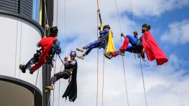 Técnicos especializados en acceso mediante cuerdas, vestidos de superhéroes, descienden en rápel por la fachada del Hospital Infantil del Hospital Universitario de Lausana (CHUV) para conmemorar el primer aniversario del nuevo edificio en Lausana.